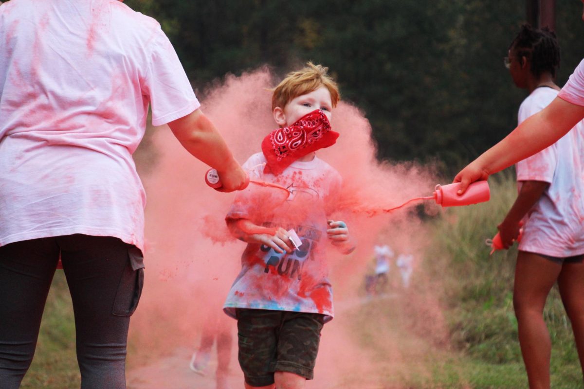Feature Photo, Superior: Running through one of several color stations, Silas Jones (K) has his shirt turned the color of his hair and the bandanna he used to cover his nose and mouth. Several of the kids wore a face covering to keep from inhaling the paint.